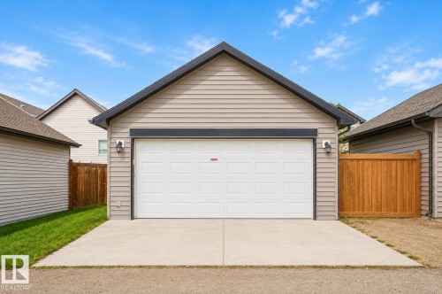 Detached garage featuring panel siding, a pitched roof, and a white overhead door - 445 Watt Boulevard Sw, Edmonton, AB 