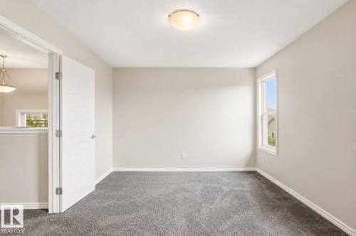 Neutral wall paint, gray carpet flooring, white trim, single-pane window, and flush mount lighting - 445 Watt Boulevard Sw, Edmonton, AB 