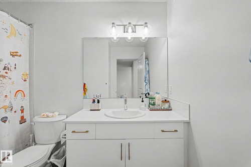 Bathroom featuring a white vanity with gold-tone hardware, an integrated sink, and a large wall mirror - #12 905 172 St Sw, Edmonton, AB - Indoor Photo Showing Bathroom