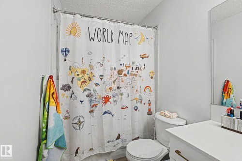 Bathroom featuring a white toilet, single vanity with white countertop, and a wall-mounted mirror - #12 905 172 St Sw, Edmonton, AB - Indoor Photo Showing Bathroom