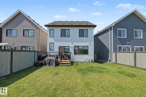 Expansive rear yard featuring a wooden privacy fence and a raised deck with black metal railings - #12 905 172 St Sw, Edmonton, AB - Outdoor