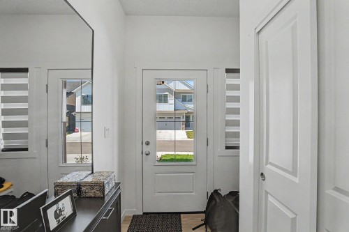 Entryway featuring a glass-paneled door, two sidelight windows with horizontal blinds, and light wood-finish flooring - #12 905 172 St Sw, Edmonton, AB - Indoor