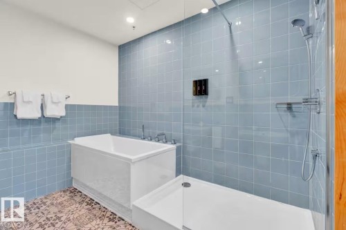 Tiled shower enclosure with glass partition, separate soaking tub, and decorative floor tiling - #903 10105 109 St Nw, Edmonton, AB 