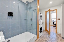 Glass-enclosed shower with blue tiled walls and a white shower base - 