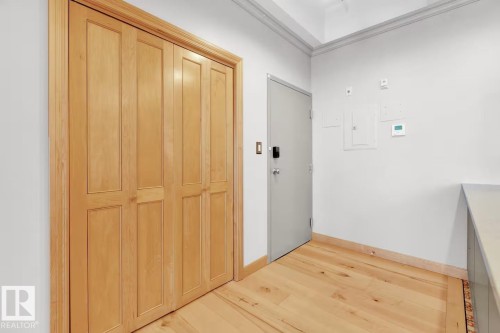 Hardwood flooring, light wood bi-fold doors, white walls, and a secure entry door - #903 10105 109 St Nw, Edmonton, AB 