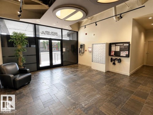 Full-height glass entry doors, large format tile flooring, track lighting, and a circular ceiling light fixture - #903 10105 109 St Nw, Edmonton, AB 