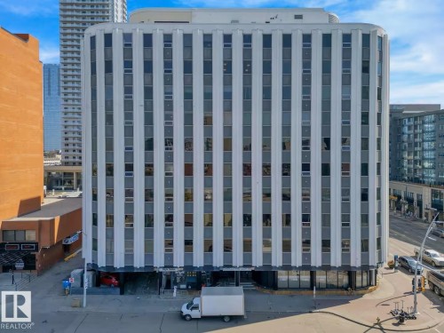Multi-story commercial building featuring a white facade with vertical gray accent panels and numerous windows - #903 10105 109 St Nw, Edmonton, AB 