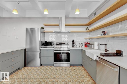 Kitchen featuring light gray cabinetry, white countertops, subway tile backsplash, stainless steel appliances, and open wood shelving - #903 10105 109 St Nw, Edmonton, AB 