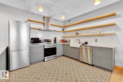Kitchen featuring stainless steel appliances, open wood shelving, gray cabinetry, subway tile backsplash, and patterned floor tile - 