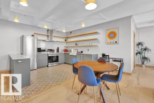 Open-concept kitchen featuring stainless steel appliances, subway tile backsplash, and light wood-finish flooring - #903 10105 109 St Nw, Edmonton, AB 