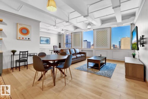 Hardwood-finish flooring, exposed beam ceiling with track lighting, multiple large windows, and built-in wall paneling - #903 10105 109 St Nw, Edmonton, AB 