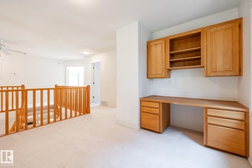Built-in desk with overhead cabinetry, wood banister and railing, and ceiling fan - 14 Highlands Place, Wetaskiwin, AB 