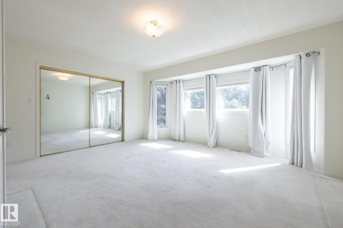 Wall-to-wall carpeting, mirrored sliding closet doors, ceiling-mounted light fixture, and a series of windows - 14 Highlands Place, Wetaskiwin, AB 