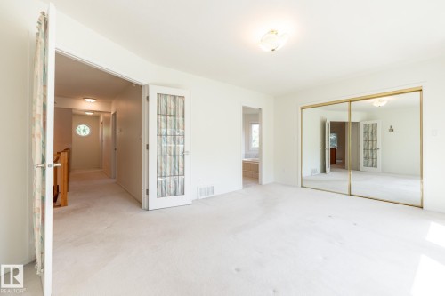 White carpeting, mirrored closet doors, and a decorative ceiling light fixture - 14 Highlands Place, Wetaskiwin, AB 