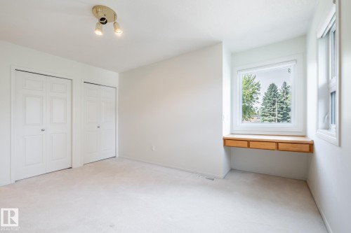 Twin bi-fold closet doors, track lighting fixture, built-in desk with three drawers, and bright window - 14 Highlands Place, Wetaskiwin, AB 