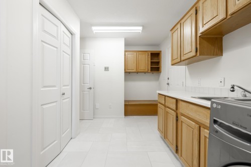 White tile flooring, wood-finish cabinetry, built-in utility sink, and white countertops - 14 Highlands Place, Wetaskiwin, AB 