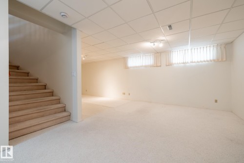 Expansive carpeted area with drop ceiling, recessed lighting, and two windows - 14 Highlands Place, Wetaskiwin, AB 