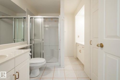 Bathroom featuring a shower stall with sliding glass doors, white vanity with integrated sink, white cabinetry with brass-toned hardware, and tiled flooring - 14 Highlands Place, Wetaskiwin, AB 
