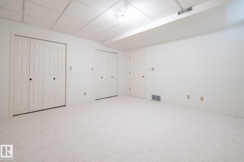 White carpeting, drop ceiling, white walls, and multiple panel doors - 14 Highlands Place, Wetaskiwin, AB 