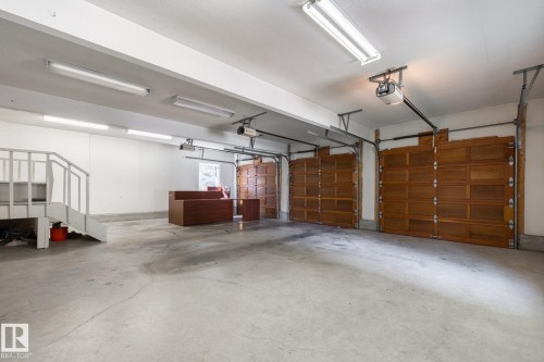 Three wooden garage doors, multiple fluorescent ceiling lights, and concrete flooring - 14 Highlands Place, Wetaskiwin, AB 