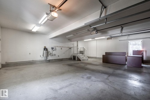 Spacious garage with concrete flooring, multiple fluorescent lighting fixtures, and a built-in staircase - 14 Highlands Place, Wetaskiwin, AB 