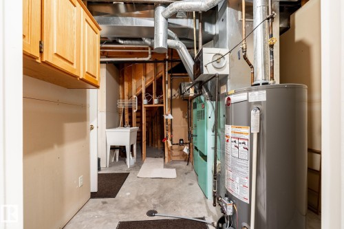 Laundry area featuring wood-finish cabinetry, utility sink, and concrete flooring - 14 Highlands Place, Wetaskiwin, AB 