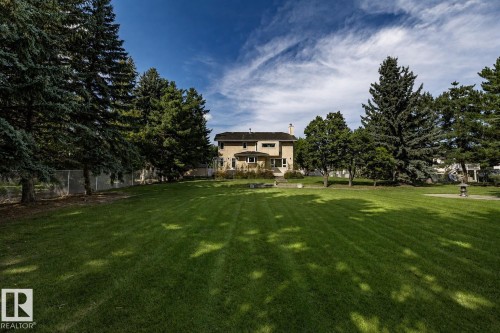 Expansive green lawn with mature trees and a beige exterior residence - 14 Highlands Place, Wetaskiwin, AB 