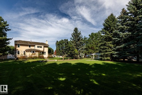 Expansive lawn area featuring a white gazebo, mature evergreen trees, and a two-story residence with a bay window - 14 Highlands Place, Wetaskiwin, AB 