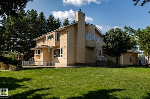Expansive green lawn surrounding a multi-level residence with stucco exterior and a spacious wood-finish deck - 14 Highlands Place, Wetaskiwin, AB 
