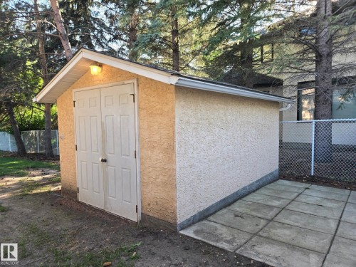 Detached storage shed with textured exterior, double panel doors, and an attached outdoor light fixture.  New shingles on shed, power to shed. - 14 Highlands Place, Wetaskiwin, AB 
