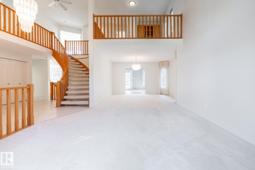 Grand foyer featuring a spiral staircase with wood railings, a second-story landing, and a chandelier - 14 Highlands Place, Wetaskiwin, AB 