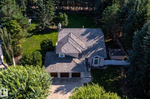 Pitched roofline with multiple gables, extensive green lawn, mature trees, three-car garage, and a garden shed - 14 Highlands Place, Wetaskiwin, AB 