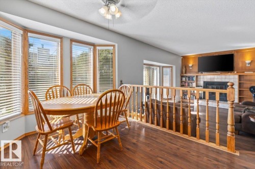 Bay window with wood-finish framing, wood-finish flooring, half-wall with wood-finish railing, vaulted ceiling, and built-in shelving with fireplace - 8015 158 Ave Nw, Edmonton, AB 