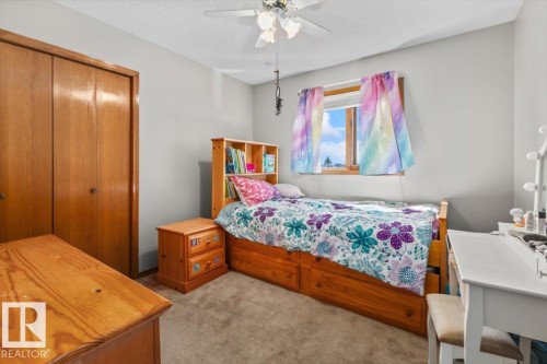 Built-in closet with wood-finish double doors, wood-frame window, and ceiling fan with light fixture - 8015 158 Ave Nw, Edmonton, AB 