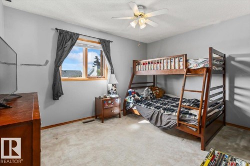 Carpeted flooring, a window with wood trim, and a ceiling fan with integrated lighting - 8015 158 Ave Nw, Edmonton, AB 