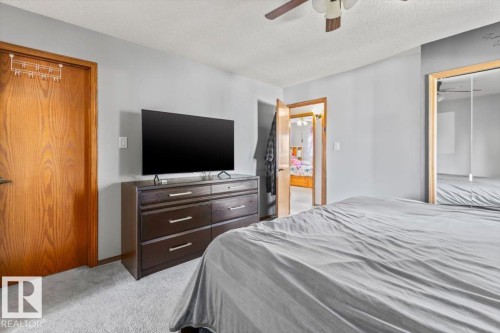 Carpeted flooring, wood-finish doors, mirrored closet doors, and a ceiling fan - 8015 158 Ave Nw, Edmonton, AB 