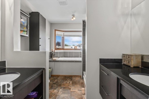 Dual vanity with dark wood-finish cabinetry, black countertops, and undermount sinks - 8015 158 Ave Nw, Edmonton, AB 
