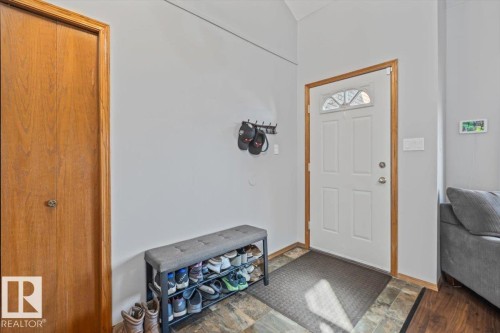 Entryway with a white paneled door, decorative transom window, wood-finish trim, and closet with wood-finish doors - 8015 158 Ave Nw, Edmonton, AB 