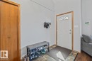 Entryway with a white paneled door, decorative transom window, wood-finish trim, and closet with wood-finish doors - 8015 158 Avenue Nw, Edmonton, AB 