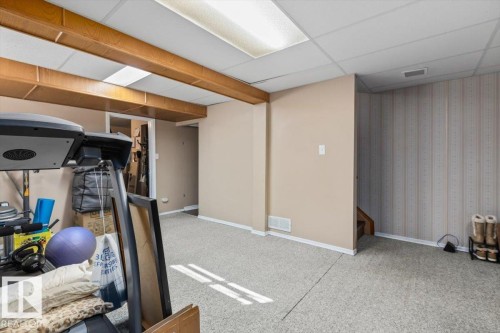 Carpeted flooring, wood-finish ceiling beams, drop ceiling with integrated lighting, textured wall covering - 8015 158 Ave Nw, Edmonton, AB 