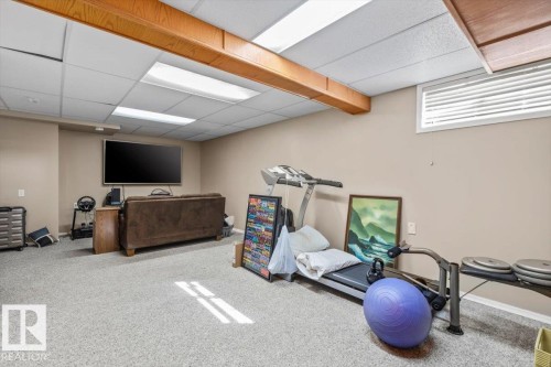 Recreational room with neutral-toned walls, light-colored carpet, and a drop ceiling - 8015 158 Ave Nw, Edmonton, AB 