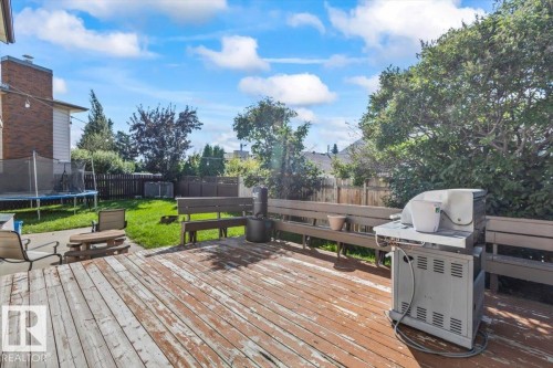 Expansive wood deck with built-in bench seating, leading to a green lawn area - 8015 158 Ave Nw, Edmonton, AB 