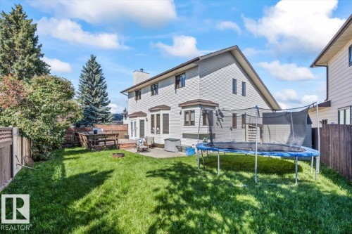 Expansive backyard featuring a manicured lawn, multi-level wooden deck, and a stone patio area - 8015 158 Ave Nw, Edmonton, AB 