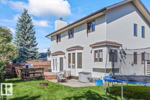 Expansive green lawn with a tiered wood deck, concrete patio, and a fire pit - 8015 158 Ave Nw, Edmonton, AB 