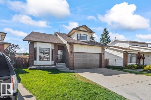 Brick and siding exterior with a peaked roofline, front-facing garage, and concrete driveway - 8015 158 Ave Nw, Edmonton, AB 