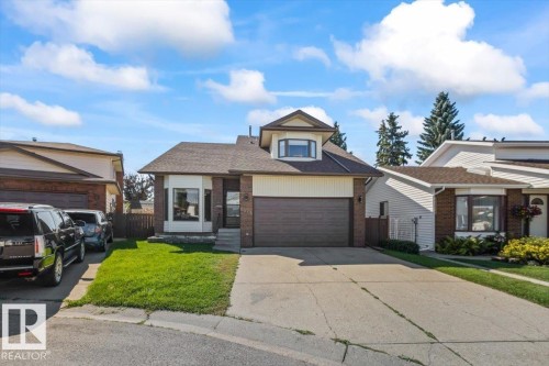 Brick facade with complementary siding, integrated garage, concrete driveway, and a dormer window - 8015 158 Ave Nw, Edmonton, AB 