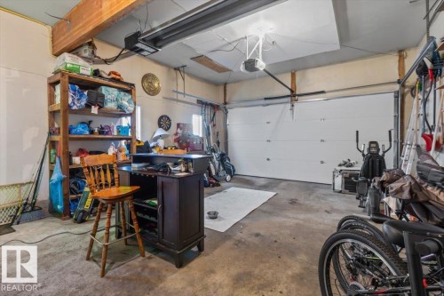 Attached garage with overhead door, exposed wooden ceiling beam, and concrete flooring - 8015 158 Ave Nw, Edmonton, AB 