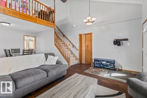 Vaulted ceiling with an attached chandelier, wood-finish flooring, and a wooden staircase with balusters - 8015 158 Ave Nw, Edmonton, AB 