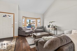Vaulted ceiling, wood-finish flooring, bay window, light gray wall finishes, and a paneled entry door with transom window - 