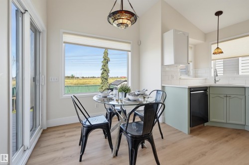 Light wood-finish flooring, white subway tile backsplash, white countertops, dual-tone cabinetry, and a large window - 839 Blacklock Way Sw, Edmonton, AB 